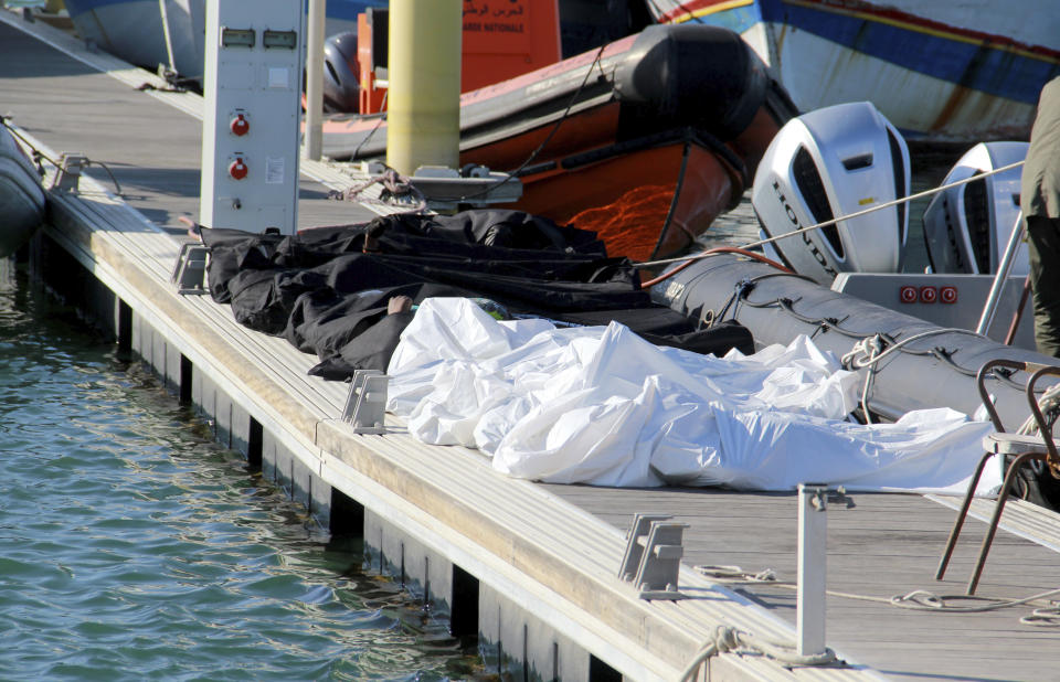 Covered dead bodies of migrants are pictured in the port of Sfax, central Tunisia, Thursday, Dec. 24, 2020. About 20 African migrants were found dead Thursday after their smuggling boat sank in the Mediterranean Sea while trying to reach Europe, Tunisian authorities said. Coast guard boats and local fishermen found and retrieved the bodies in the waters off the coastal city of Sfax in central Tunisia. (AP Photo/Houssem Zouari)