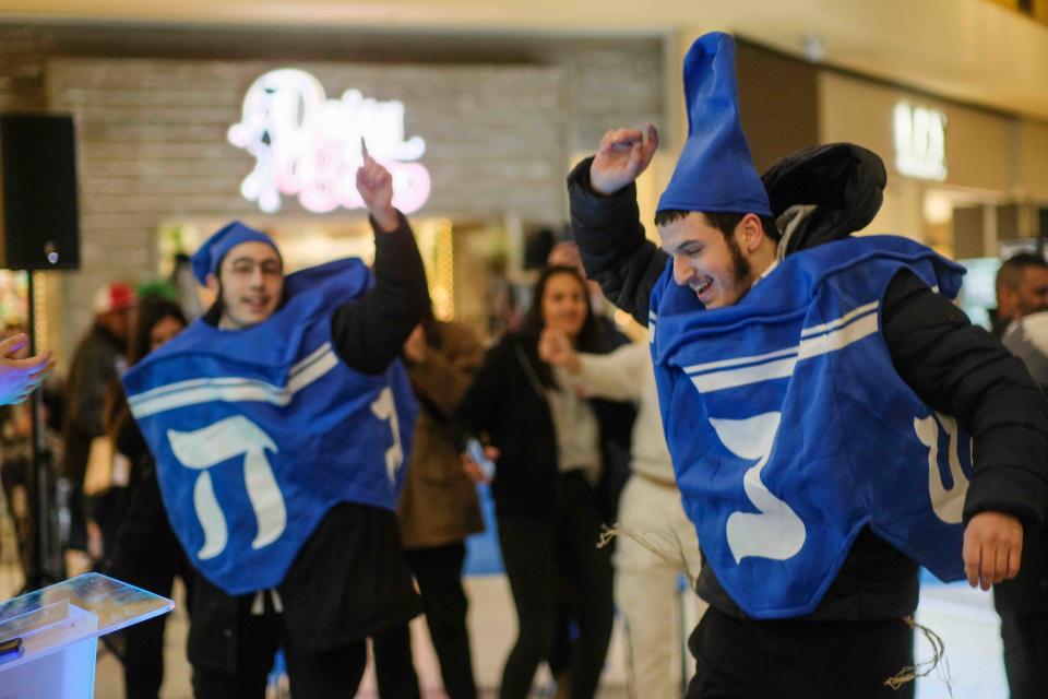 A duo of dancing dreidels help the Westgate mall crowd celebrate Hanukkah Thursday evening in Amarillo.