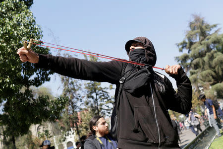 A demonstrator with a slingshot clashes with riot police during a protest demanding an end to profiteering in the education system in Santiago, Chile April 19, 2018. REUTERS/Pablo Sanhueza NO RESALES. NO ARCHIVE.