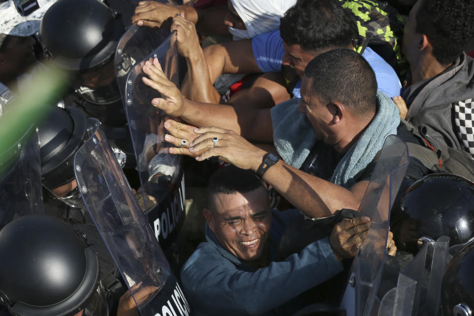 Migrantes forcejean con la Guardia Nacional mexicana en el cruce fronterizo entre Guatemala y México en Tecún Umán, Guatemala, el sábado 18 de enero de 2020. (AP Foto/Marco Ugarte)