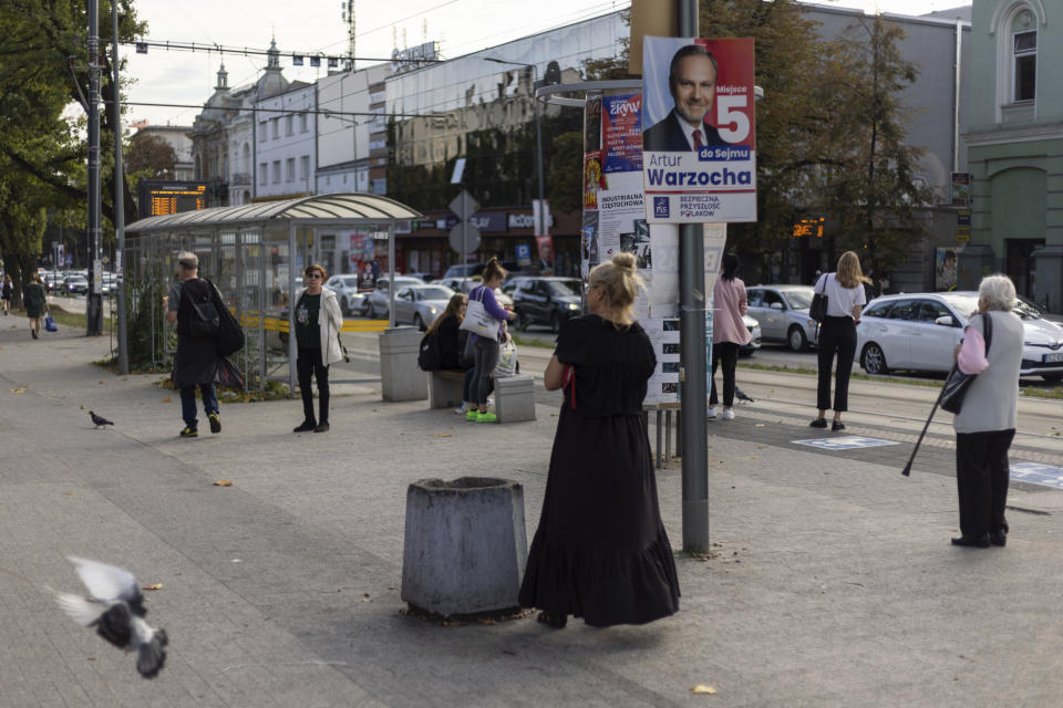 People wait at a tram stop in Czestochowa's downtown, Poland, Tuesday, Oct. 3, 2023. As the ruling conservative Law and Justice party seeks to win an unprecedented third straight term in the Oct. 15 parliamentary election, it has sought to bolster its image as a defender of Christian values and traditional morality. Yet more and more Poles appear to be questioning their relationship with the Catholic church, and some cite its closeness to the government as a key reason. (AP Photo/Michal Dyjuk)