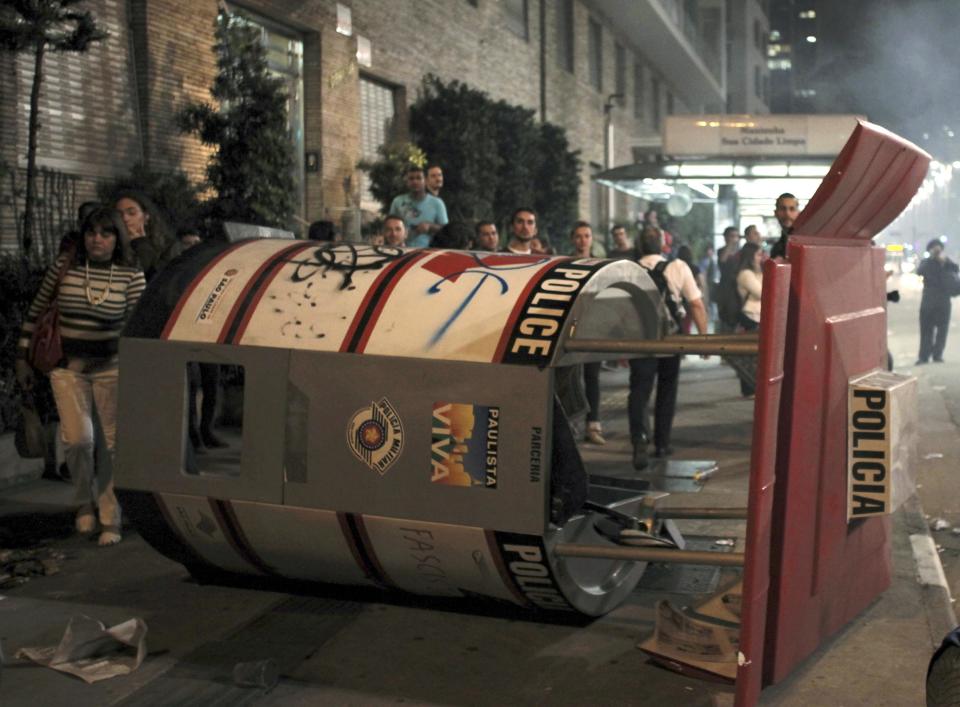 Residents walk past a destroyed police booth during a protest against the 2014 World Cup at Paulista Avenue in Sao Paulo