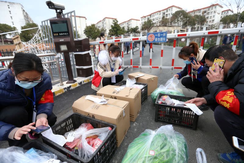 FILE PHOTO: Volunteers and community workers deliver vegetables and goods to residents inside a residential compound at its entrance, in Xiangyang