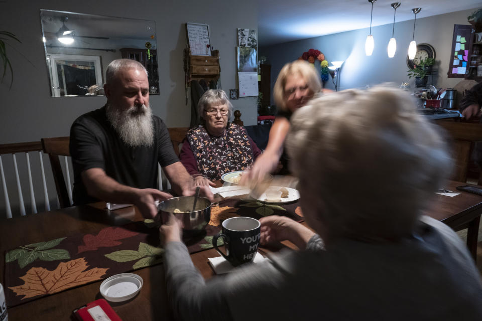 Bill Bednarowski, left, and Susan Ryder, right, children of Betty Bednarowski, center, clear the dinner table, Tuesday, Nov. 30, 2021, in Rotterdam Junction, N.Y. (AP Photo/Wong Maye-E)