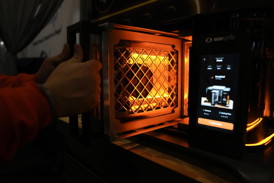 An exhibitor provides a demonstration of the Perfecta AI grill by Seer Grills during the CES tech show Wednesday, Jan. 10, 2024, in Las Vegas. (AP Photo/Ryan Sun)