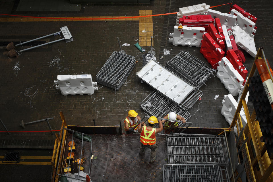 Workers load barriers used by protesters into a truck near the Legislative Council building in Hong Kong, Wednesday, July 3, 2019. A pro-democracy lawmaker who tried to stop Hong Kong protesters from breaking into the legislature this week says China will likely use the vandalizing of the building as a reason to step up pressure on the Chinese territory. (AP Photo/Andy Wong)