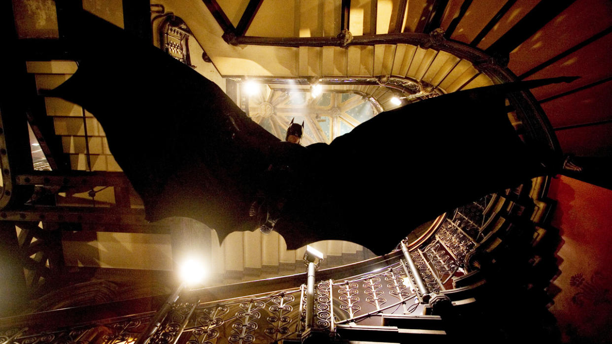  Batman glides down a staircase to evade gunfire in Batman Begins. 