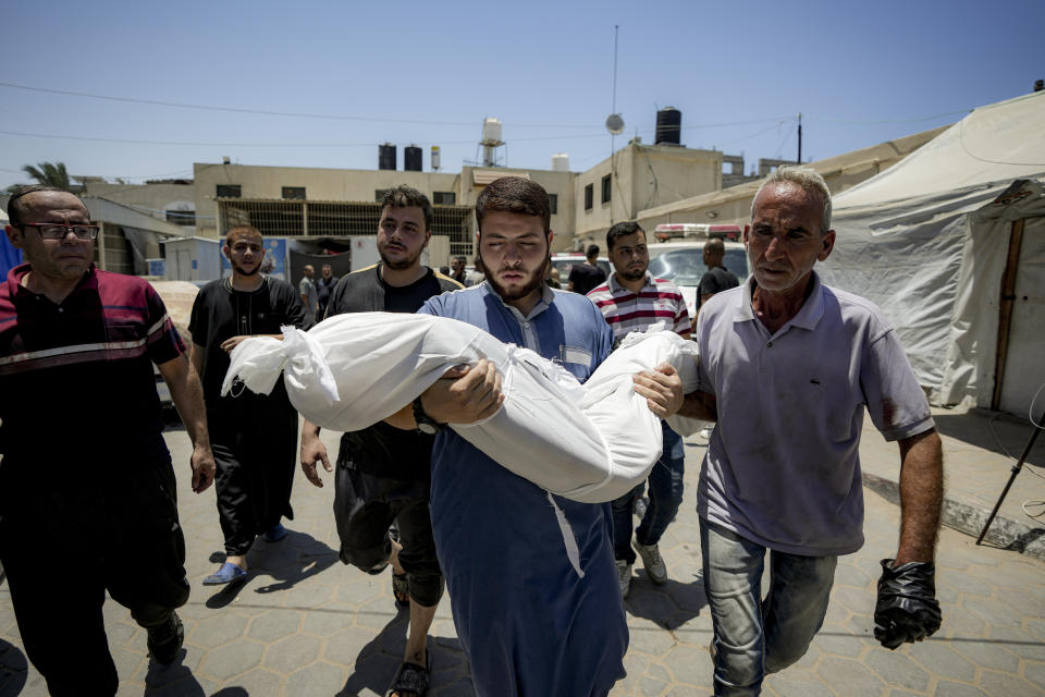 A Palestinian man holds the body of a child killed in the Israeli bombardment of the Gaza Strip, at a hospital morgue in Deir al-Balah, Tuesday, July 9, 2024. (AP Photo/Abdel Kareem Hana)