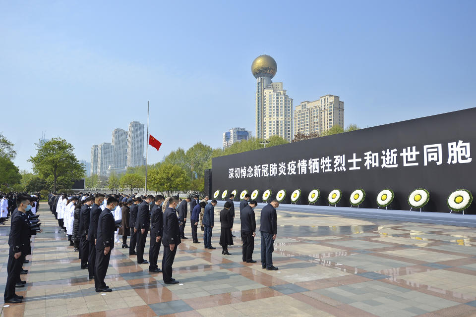 People bow their heads during a national moment of mourning for victims of coronavirus at an official ceremony in Wuhan in central China's Hubei Province, Saturday, April 4, 2020. With air raid sirens wailing and flags at half-staff, China on Saturday held a three-minute nationwide moment of reflection to honor those who have died in the coronavirus outbreak, especially "martyrs" who fell while fighting what has become a global pandemic. (Chinatopix via AP)