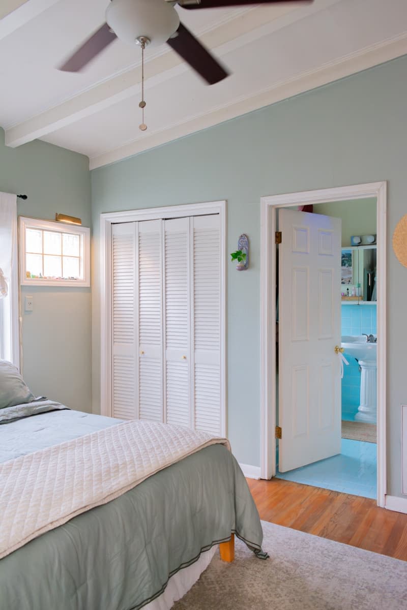 Accordion closet doors with doorways to a blue-tiled bathroom.