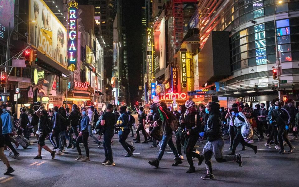 Protesters rush past Times Square after an 11pm curfew during a night of marches and vandalism in NYC - Getty