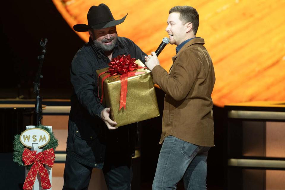 <p>Chris Hollo/Grand Ole Opry</p> Garth Brooks invites Scotty McCreery to join the Grand Ole Opry on Dec. 3, 2023 in Nashville