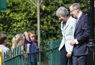 Britain's Prime Minister Theresa May and her husband Philip talk to children as they arrive at a polling station to vote in the European Elections in Sonning, England, Thursday, May 23, 2019.(AP Photo/Frank Augstein)