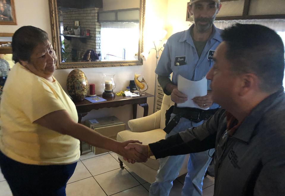 Debbie Hernandez shakes hands with Lighting Inc. General Manager Gabriel Trinidad after he and electrician Jason Chedester inspected her home Wednesday. “It’s a big, big blessing to have light everywhere,” Hernandez said.