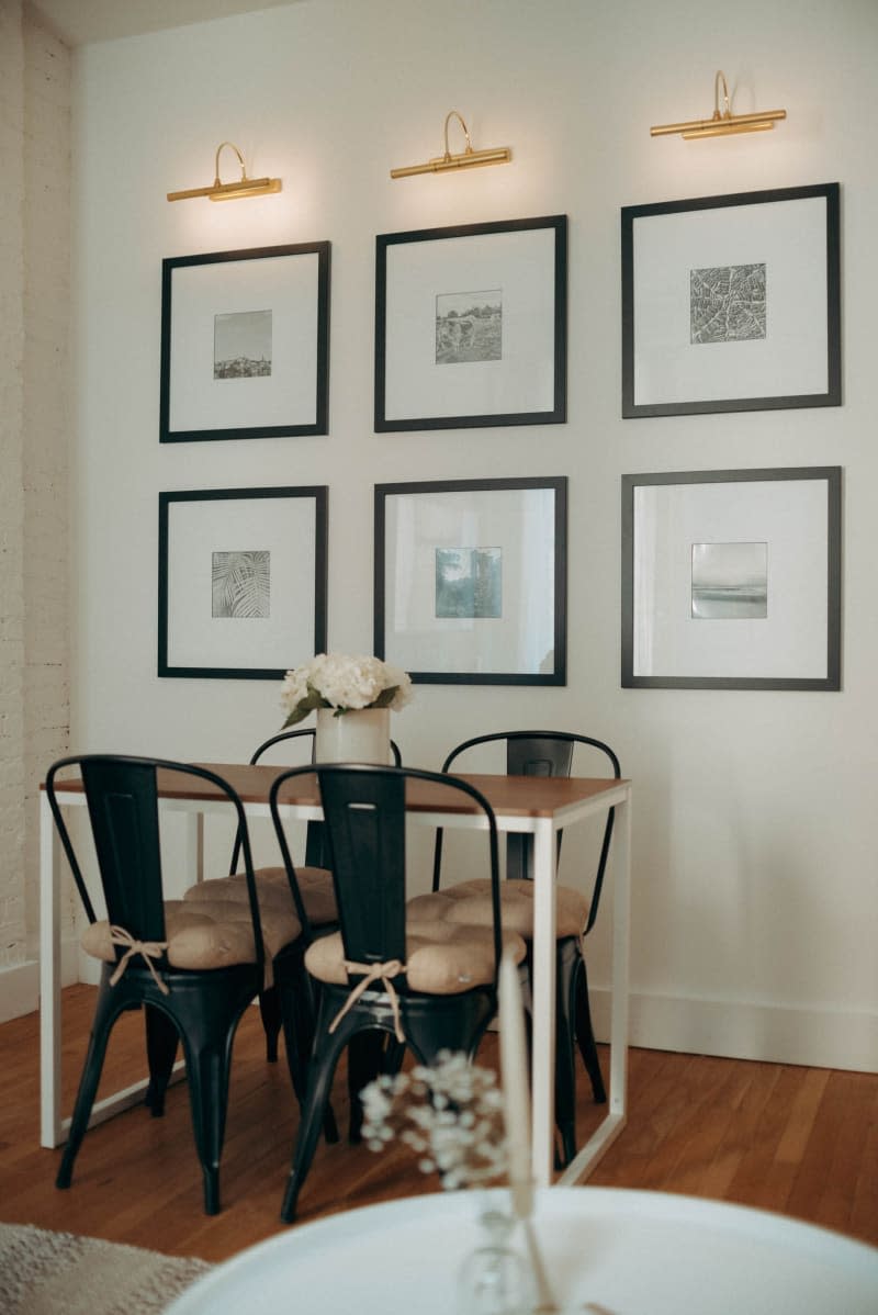 A gallery wall with lights behind a dining table