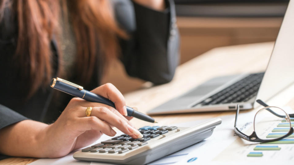 edit Woman calculating figures next to a laptop