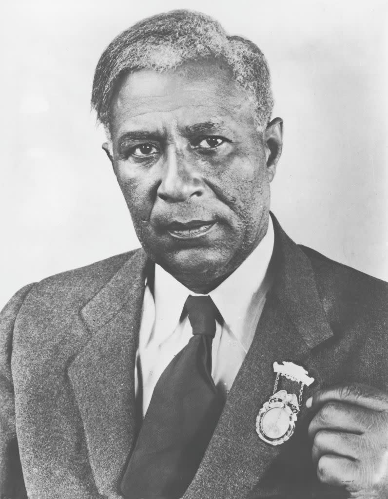 black and white photo of garrett morgan, he looks at the camera and wears a wool jacket, collared shirt and tie, he has a medal on his jacket lapel