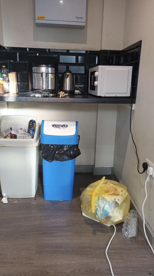 Kitchen counter with appliances, a blue recycling bin, and a trash bag