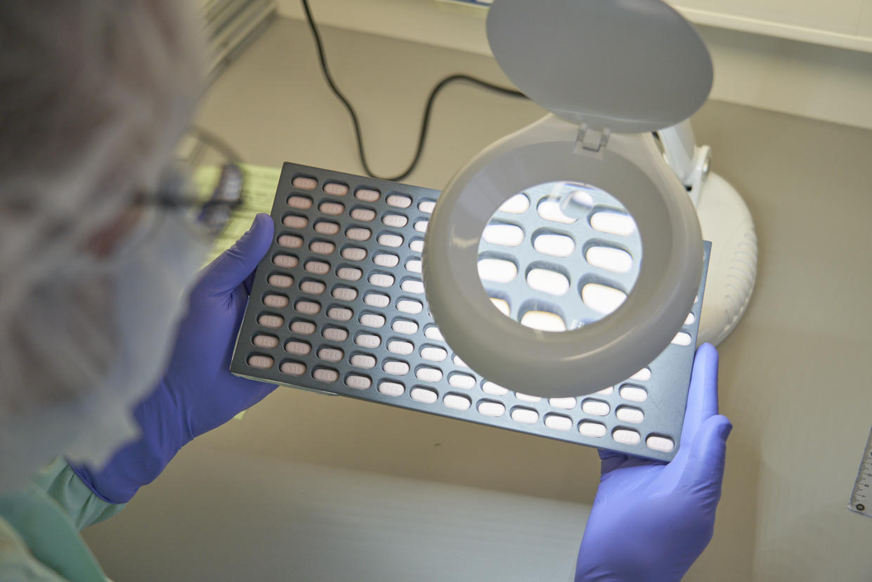 A lab technician visually inspects Paxlovid tablet samples in Freiburg, Germany. 