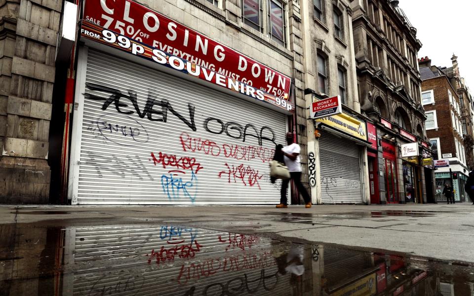 A pedestrian passes a shuttered closed souvenir shop