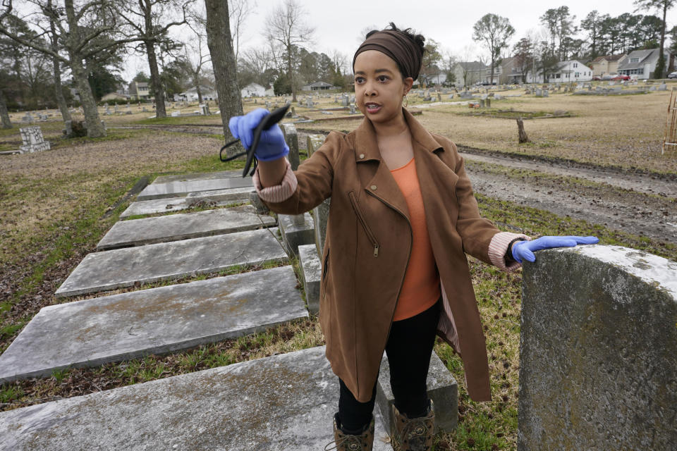 Nadia Orton, a genealogist and family historian in Virginia, points out dilapidated areas next to tombstones at the Lincoln Memorial Cemetery in Portsmouth, Va., Tuesday, March 23, 2021. Orton has worked tracing her own family and others to historically Black cemeteries. (AP Photo/Steve Helber)