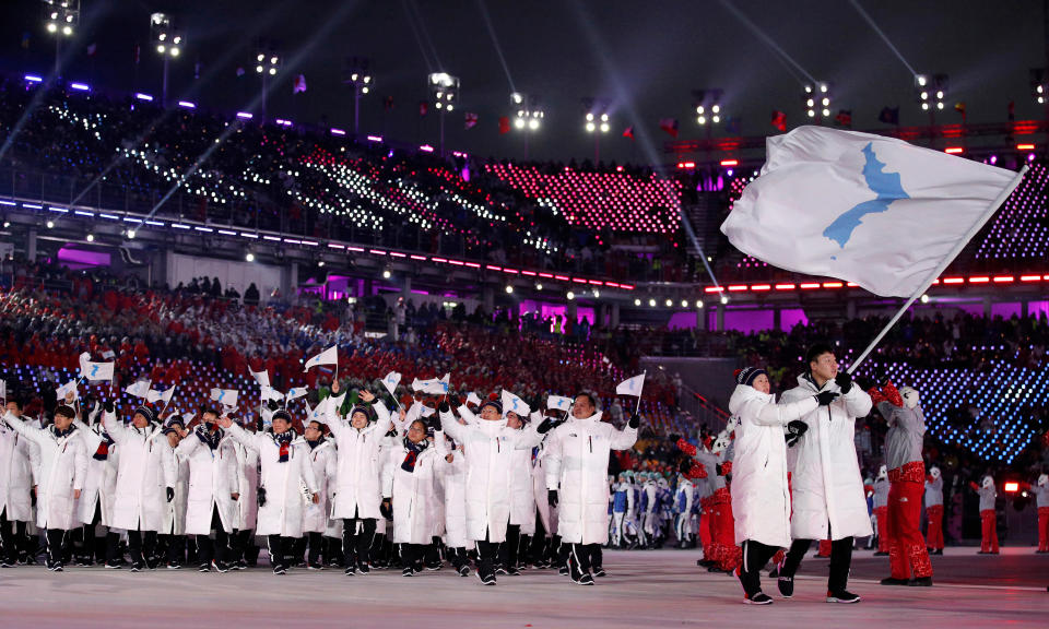 FILE - North Korea's Hwang Chung Gum and South Korea's Won Yun-jong carry the unification flag during the opening ceremony of the 2018 Winter Olympics in Pyeongchang, South Korea on Feb. 9, 2018. North Korea basked in the global limelight during the last Winter Games in South Korea, with hundreds of athletes, cheerleaders and officials pushing hard to woo their South Korean and U.S. rivals in a now-stalled bid for diplomacy. Four years later, as the 2022 Winter Olympics come to its main ally and neighbor China, North Korea isn't sending any athletes and officials because of coronavirus fears. (AP Photo/Jae C. Hong, File)