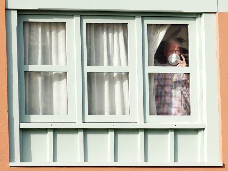 A tourist looks through a window of the H10 Costa Adeje Palace hotel, which is on lockdown after novel coronavirus has been confirmed in Adeje