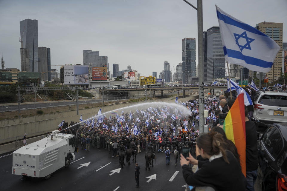 Israeli police use a water cannon to disperse Israelis blocking the freeway during a protest against plans by Prime Minister Benjamin Netanyahu's government to overhaul the judicial system in Tel Aviv, Israel, Thursday, March 23, 2023. (AP Photo/Oded Balilty)