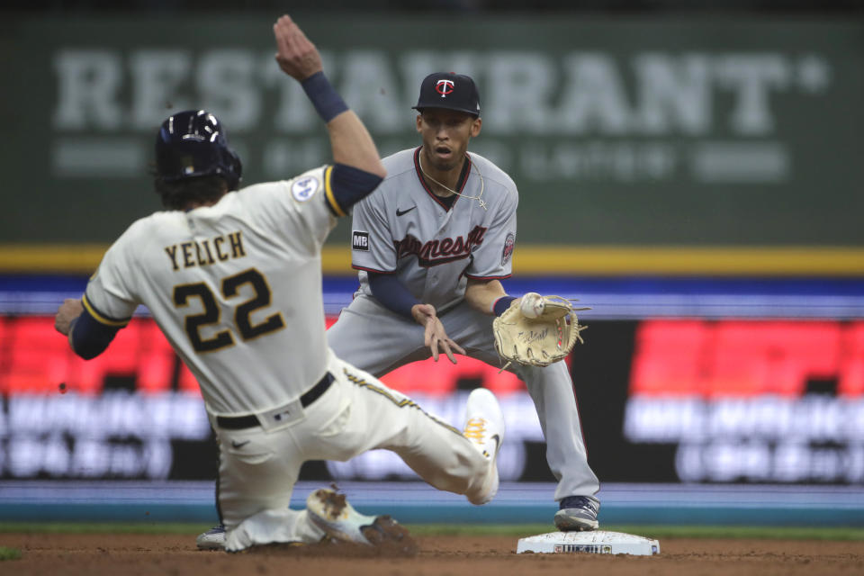 Milwaukee Brewers' Christian Yelich (22) slides in safely at second base as Minnesota Twins' Andrelton Simmons is unable to handle a throw during the fifth inning of an Opening Day baseball game Thursday, April 1, 2021, in Milwaukee. (AP Photo/Aaron Gash)