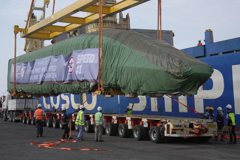 Workers lower an electric multiple unit, part of Chinese-made high-speed passenger train, onto a truck at Tanjung Priok Port in Jakarta, Indonesia, Friday, Sept. 2, 2022. The first high-speed electric train which is prepared for the Jakarta-Bandung High-Speed Railway arrived in the capital city on Friday. (AP Photo/Dita Alangkara)