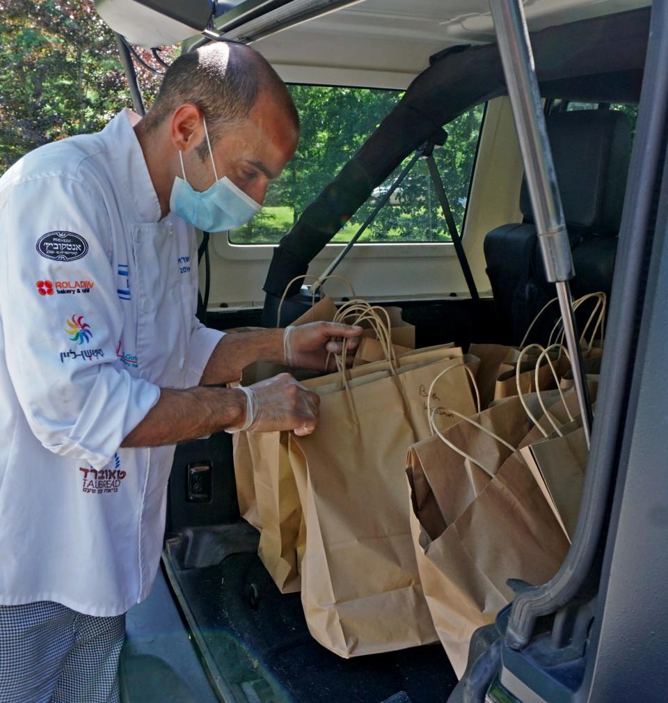Back in early 2020, Bun's Bakery's Guy Hanuka selects an order from the bags in the back of his car to be delivered to a customers at the pickup point at Lippitt Park in Providence.