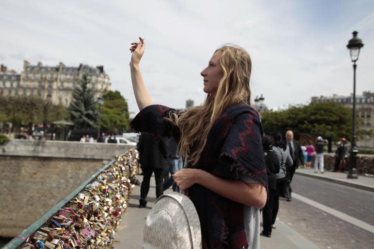 A woman throws a padlock's key in the Seine after locking a padlock on the "Pont Notre-Dame" on May 29, 2015, in Paris