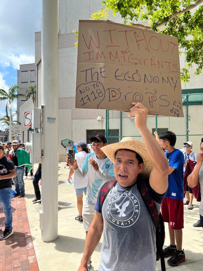 A SB 1718 protester in Fort Myers waves a sign in support of the immigrant community. People in cities across the state are marching in opposition to a new immigration law pushed by Gov. Ron DeSantis.