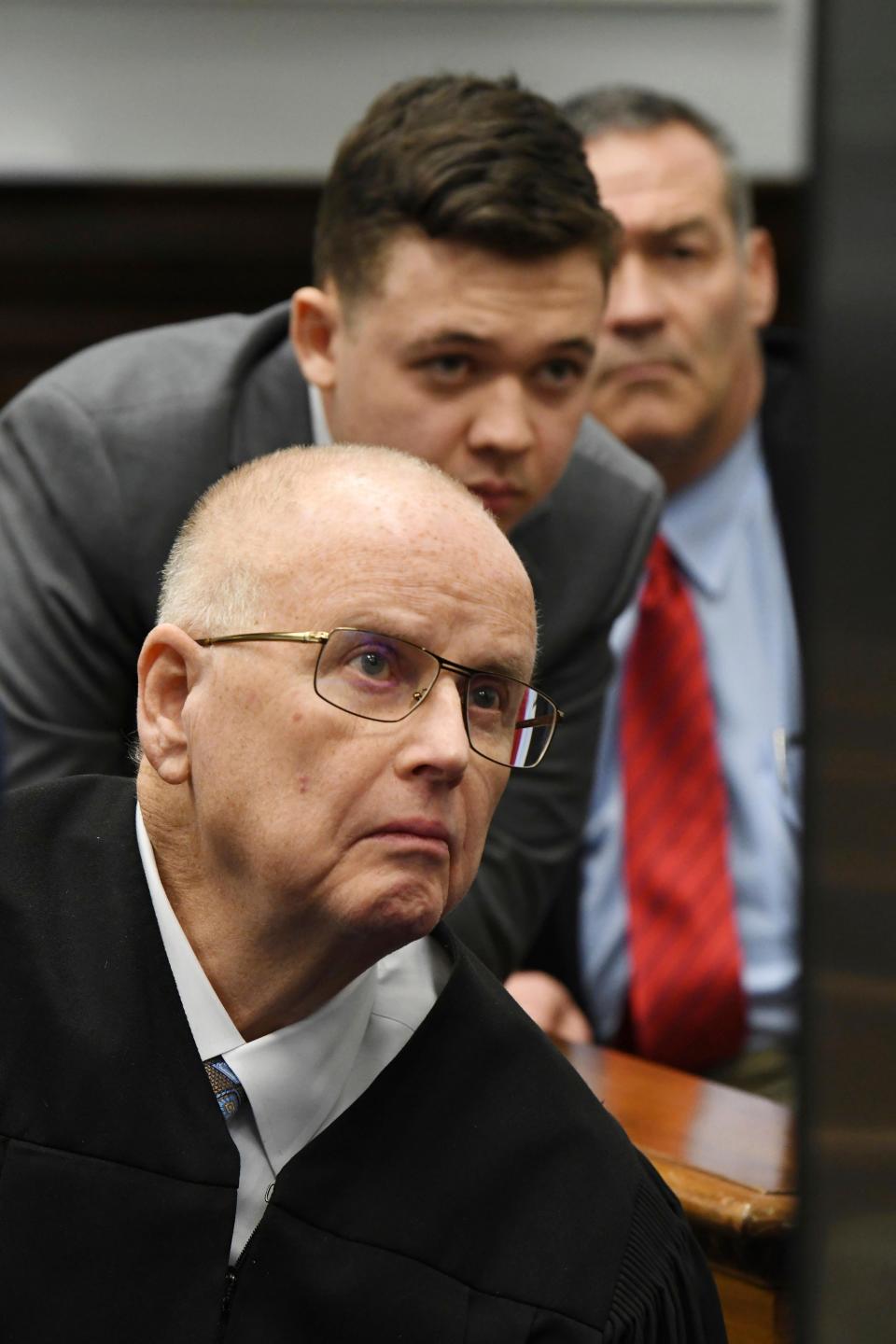 Judge Bruce Schroeder is seated in front of a large video monitor as Kyle Rittenhouse and attorneys for both sides argue about a video at the Kenosha County Courthouse in Kenosha, Wis., on Friday, Nov. 12, 2021. Rittenhouse is accused of killing two people and wounding a third during a protest over police brutality in Kenosha, last year.