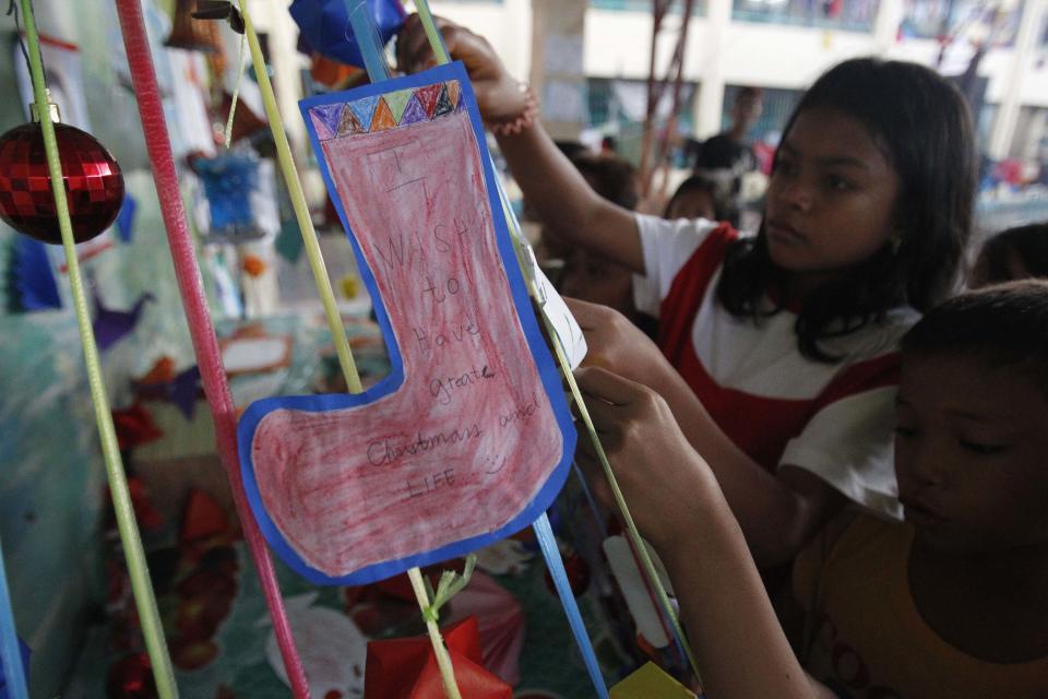 Children survivors of super Typhoon Haiyan decorate improvised Christmas tree with Christmas wishes inside evacuation centre in Tacloban