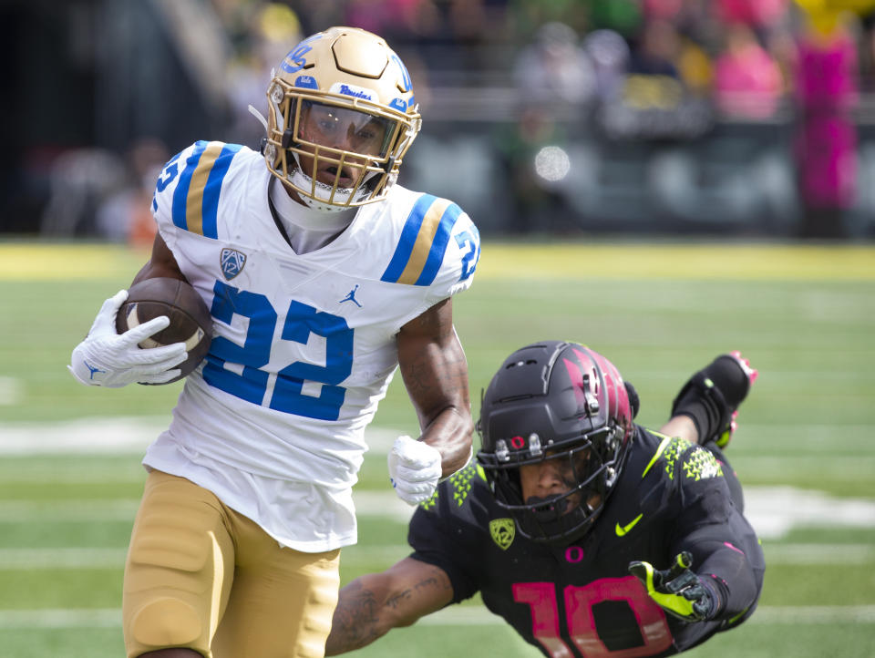 UCLA's Keegan Jones, left, runs for a touchdown ahead of a diving Oregon's Justin Flowe during the first half in an NCAA college football game Saturday, Oct. 22, 2022, in Eugene, Ore. (AP Photo/Chris Pietsch)