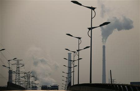 Smoke rises from chimneys of a steel plant next to a viaduct on a hazy day in Tangshan, Hebei province February 18, 2014. REUTERS/Petar Kujundzic