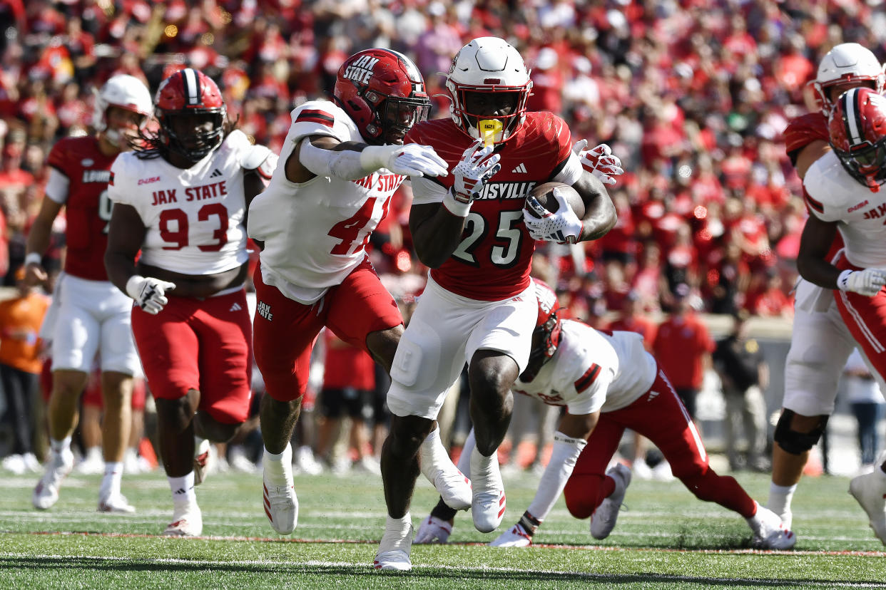 Louisville running back Isaac Brown (25) attempts to escape the grasp of Jacksonville State edge Curley Young Jr. (41) during the first half of an NCAA college football game in Louisville, Ky., Saturday, Sept. 7, 2024. (AP Photo/Timothy D. Easley)