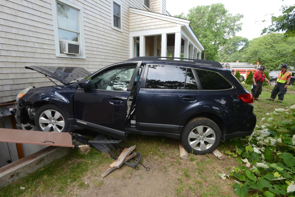 Harwich Fire Department crews look over the damage Friday morning as a car heading south swerved off Depot Street knocking over a split rail fence and then traveling several hundred feet before smashing into a home at 473 Depot St. Two people were transported from the scene to Cape Cod Hospital.