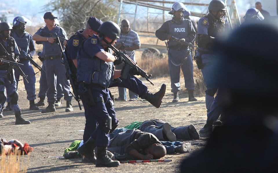 Police surround the bodies of striking miners after opening fire on a crowd at the Lonmin Platinum Mine near Rustenburg, South Africa, Thursday, Aug. 16, 2012. An unknown number of people have been killed and injured. Police moved in on workers who gathered on a rocky outcropping near the Lonmin late afternoon, firing unknown ammunition. (AP Photo) SOUTH AFRICA OUT