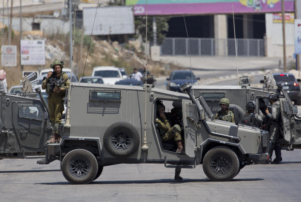 Israeli forces close the roads near the area of an attack, west of the West Bank city of Ramallah, Friday, Aug. 23. 2019. An explosion Friday near a West Bank settlement that Israel said was a Palestinian attack killed a 17-year-old Israeli girl and wounded her brother and father, Israeli authorities said. (AP Photo/Nasser Nasser)