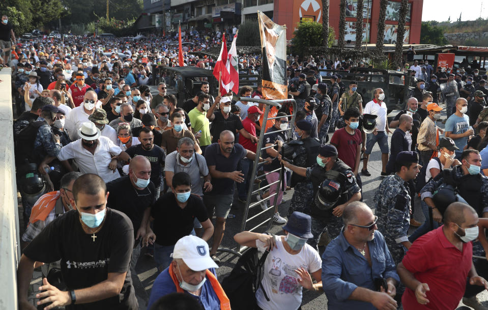 Supporters of Lebanese President Michel Aoun run to take a main road that links to the presidential palace before the arrival of the anti-government protesters, in Baabda east of Beirut, Lebanon, Saturday, Sept. 12, 2020. Lebanese soldiers on Saturday fired rubber bullets and live rounds in the air to disperse hundreds of protesters trying to march to the presidential palace during an anti-government demonstration. (AP Photo/Bilal Hussein)