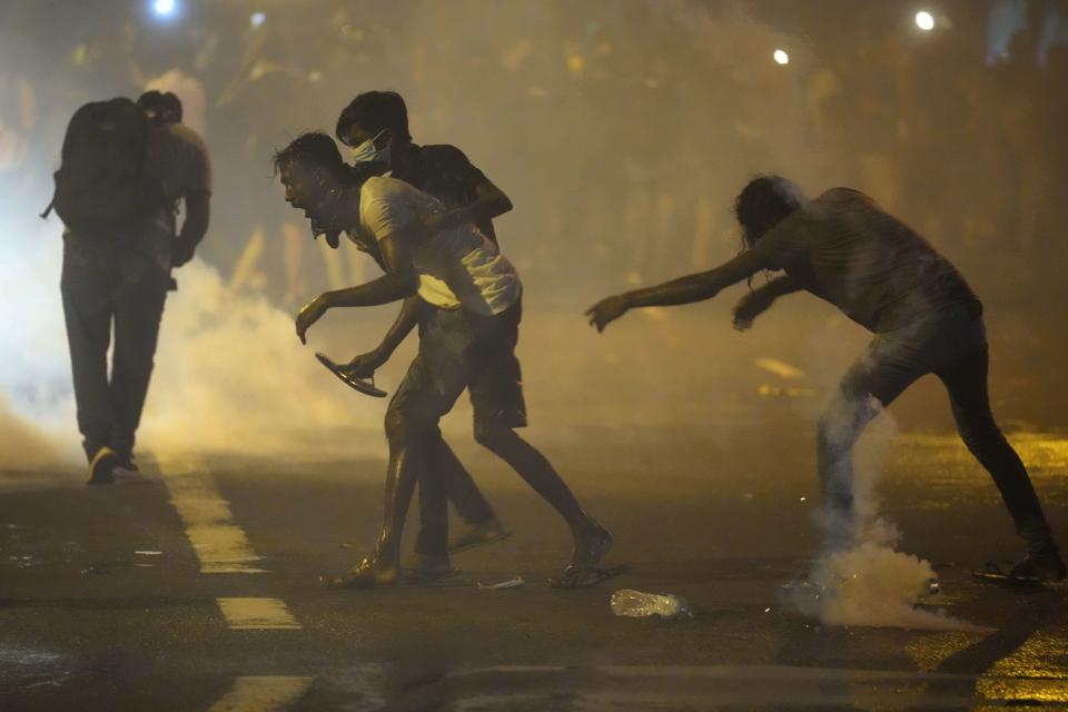 Anti-government protesters run for cover as police fire tear gas shells during a protest near the president's official residence in Colombo, Sri Lanka, Saturday, May 28, 2022. Police fired tear gas and water canon on protesters who marched toward the president Gotabaya Rajapaksa's barricaded residence demanding his resignation. (AP Photo/Eranga Jayawardena)