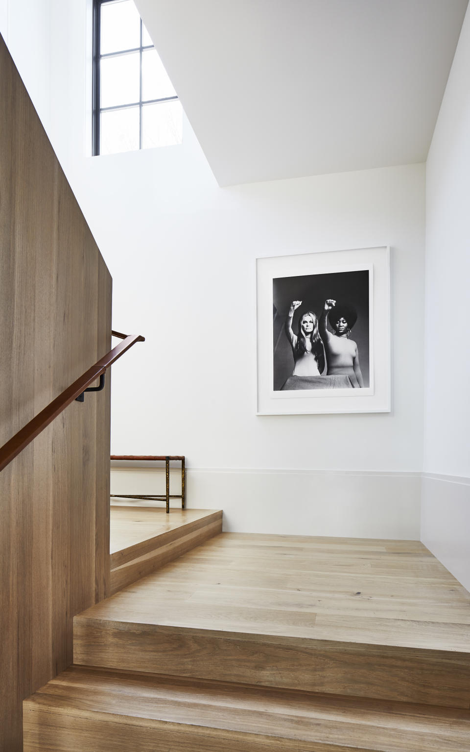 A leather handrail wraps up a stairwell's halfway surrounded by white walls