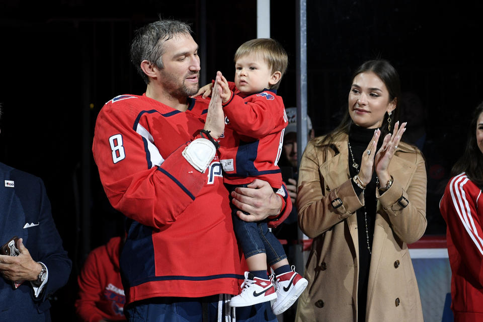 Washington Capitals left wing Alex Ovechkin, left, of Russia, son Sergei, center, and Ovechkin's wife, Nastya, right, applaud during a ceremony to honor Ovechkin for his 700th goal, before the team's NHL hockey game against the Winnipeg Jets, Tuesday, Feb. 25, 2020, in Washington. (AP Photo/Nick Wass)