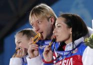 Yulia Lipnitskaya (L), Evgeni Plushenko (C) and Ksenia Stolbova of the gold medal-winning Russian figure skating team bite into their medals, during the medal ceremony for the figure skating team ice dance free dance at the Sochi 2014 Winter Olympics February 10, 2014. REUTERS/David Gray (RUSSIA - Tags: OLYMPICS SPORT FIGURE SKATING)