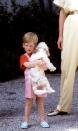 <p>A young Prince Harry carries a dog.</p>