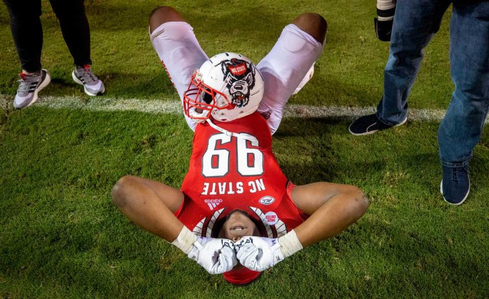 N.C. State’s Daniel Joseph (99) lies on the turf in disbelief as fans storm the field to celebrate the Wolfpack’s 27-21 overtime victory over Clemson on Saturday September 25, 2021 at Carter-Finley Stadium in Raleigh, N.C.