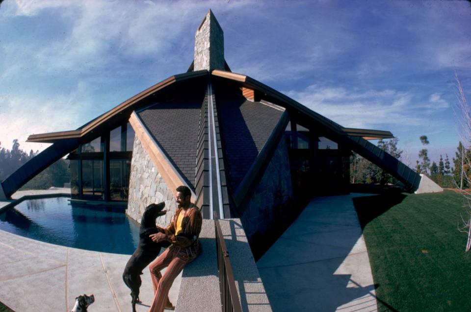 <p>Wilt Chamberlain plays with one of his pet dogs outside his specially-commissioned home, called Ursa Major, in Bel-Air, California in 1972.</p>