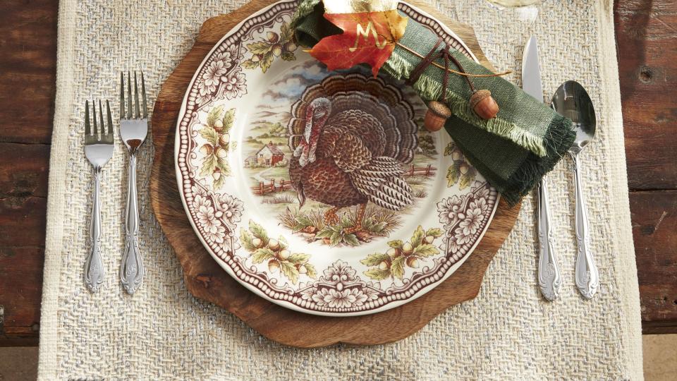 thanksgiving table with green gourds and acorn squash napkins wrapped in twine with acrons attached and a natural leaf place card painted with gold leaf